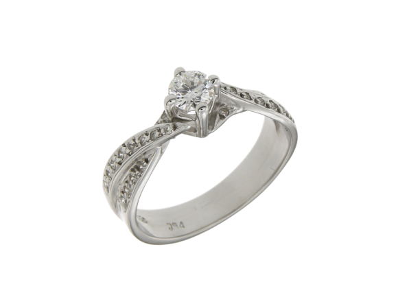Δαχτυλίδι Μονόπετρο σε Λευκόχρυσο 18K με μια φαρδιά σταυρωτή γάμπα με Διαμάντια και ένα διαμάντι κοπής Brilliant στο κέντρο